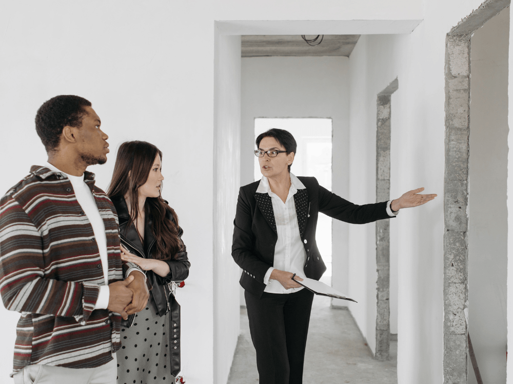 Corretora apresenta um imóvel em construção a um casal durante uma visita, etapa comum na negociação de uma locação residencial.