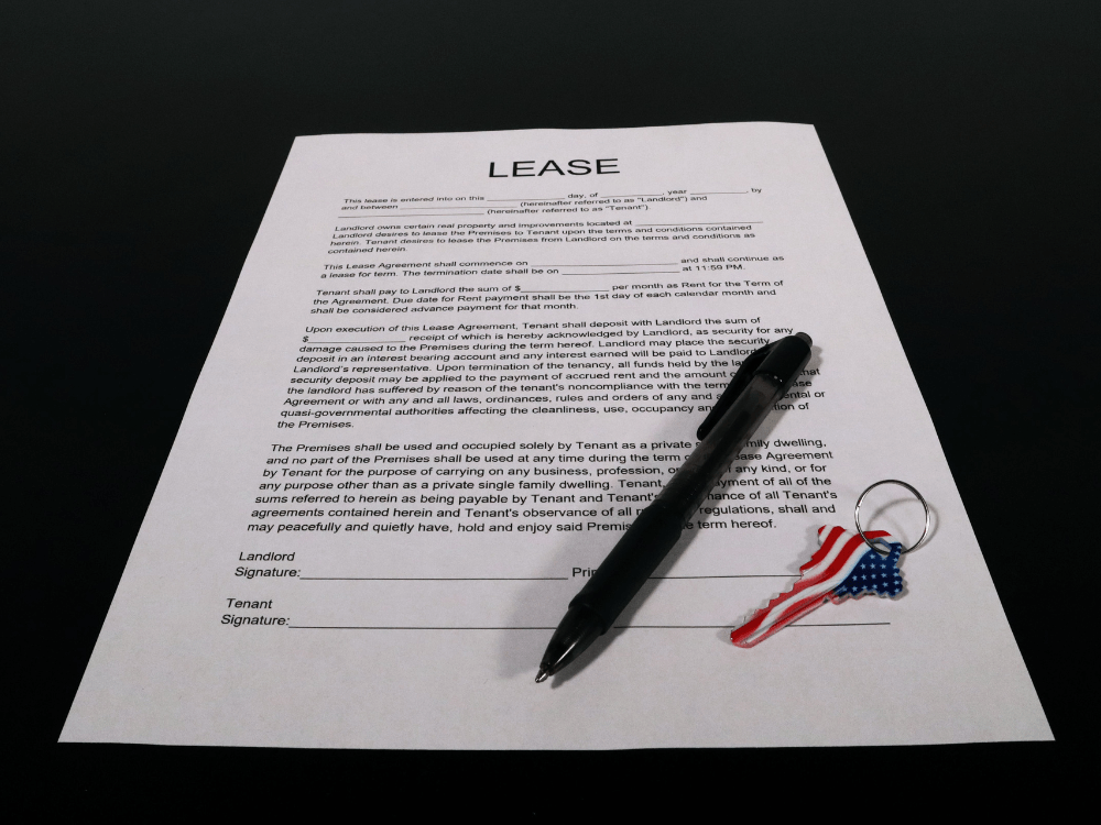 Contrato de aluguel impresso sobre uma mesa escura, acompanhado de caneta preta e chaveiro, representando o acordo de locação. Tudo para explicar a multa por quebra de contrato de aluguel.